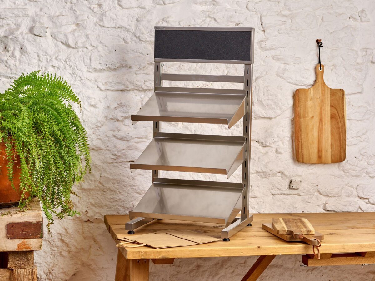 Metal display stand stood on a rustic table on a plain back drop in a retail environment