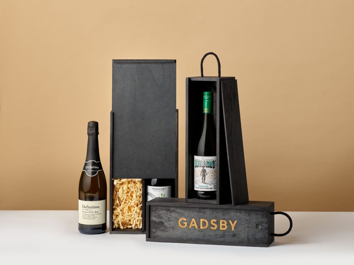 Black bottle boxes in different sizes with shredded paper and bottles of wine