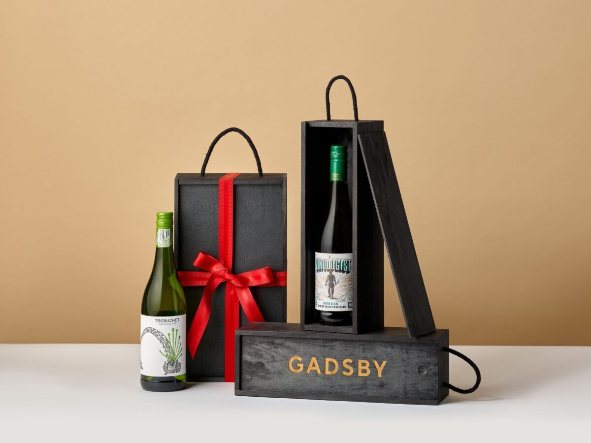 Black wooden bottle boxes stacked together with red ribbon wrapped around them