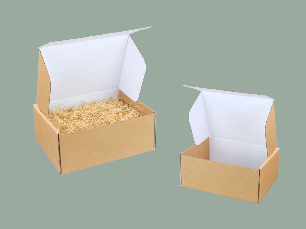 Two ecommerce hampers on a sage green background, one with shredded paper inside and the other is empty