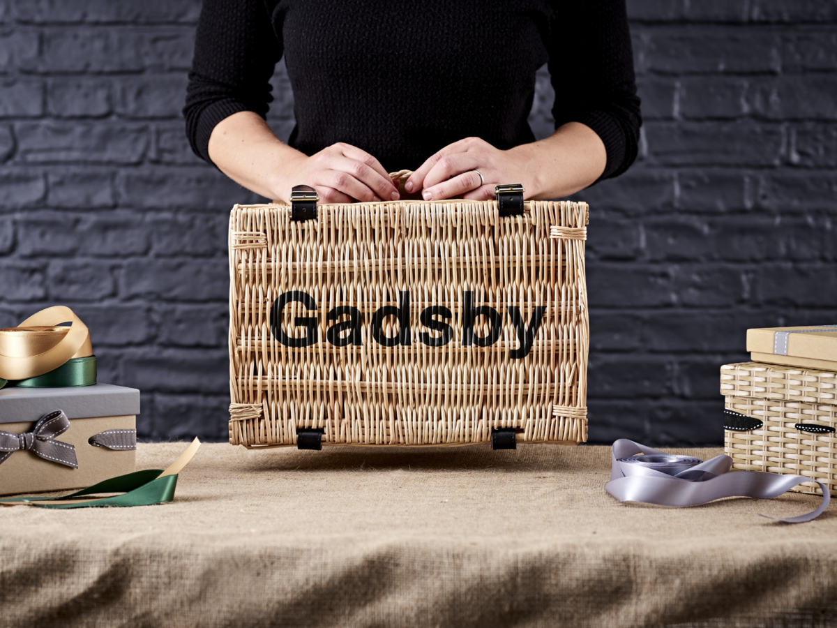 Person holding up a wicker hamper basket that has been customised with the brand Gadsby using a lid stencilling method