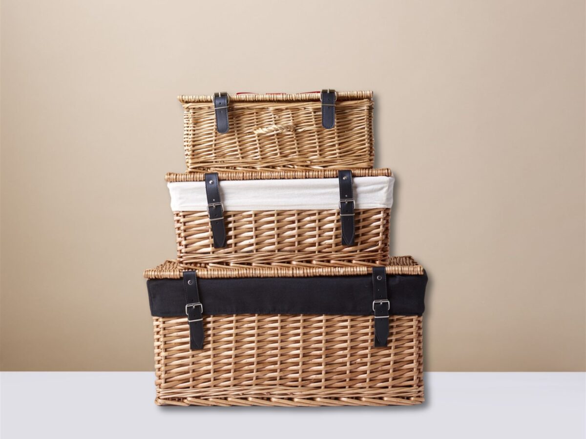 A stack of natural colour hampers in a group of three with white and black cotton liners inside the hampers