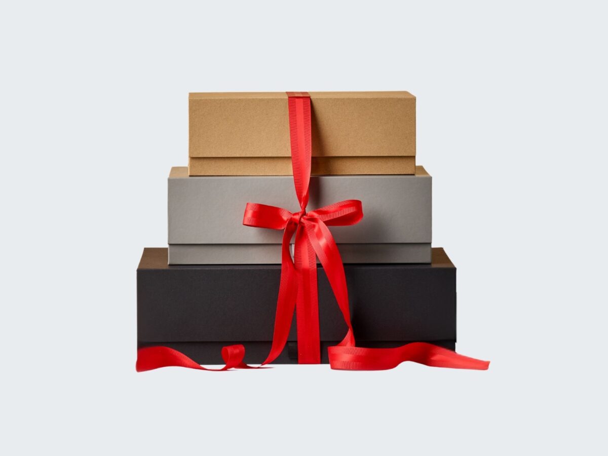 Stack of black, kraft and grey cardboard boxes with a red ribbon wrapped around them