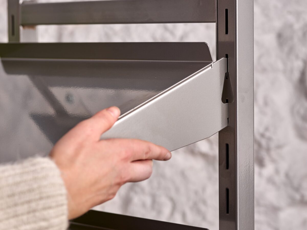 Woman placing a metal shelf onto a metal display stand