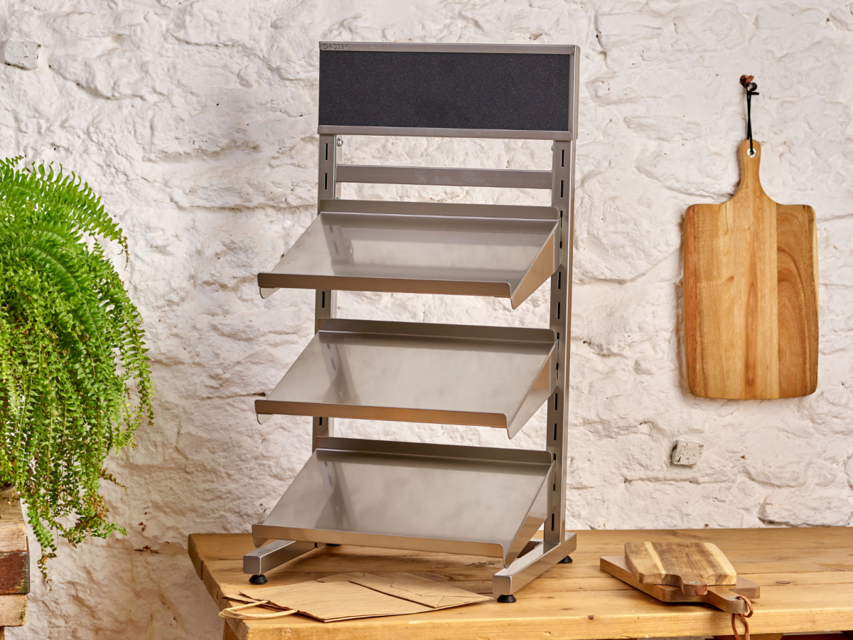 Empty retail display stand made from mild steel at the forefront of a rustic shop