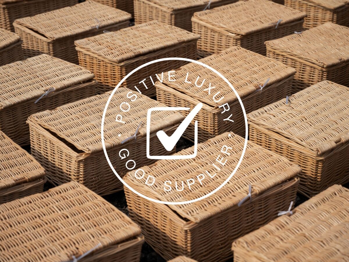 Wicker hamper baskets laid out for drying in the sun with the Positive Luxury Good Supplier logo at the front