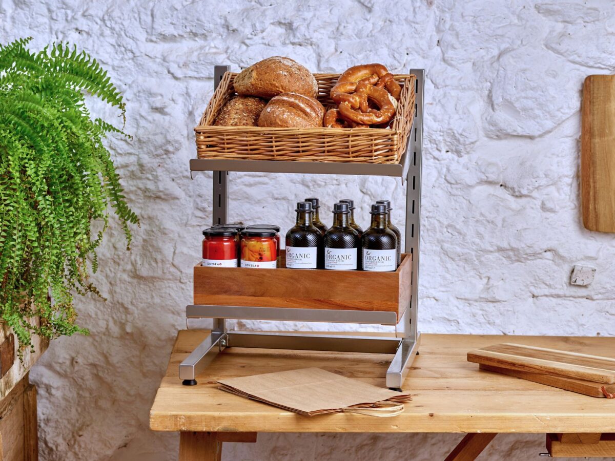 Metal display stand with a wicker basket and wooden crate on the shelves filled with fresh produce