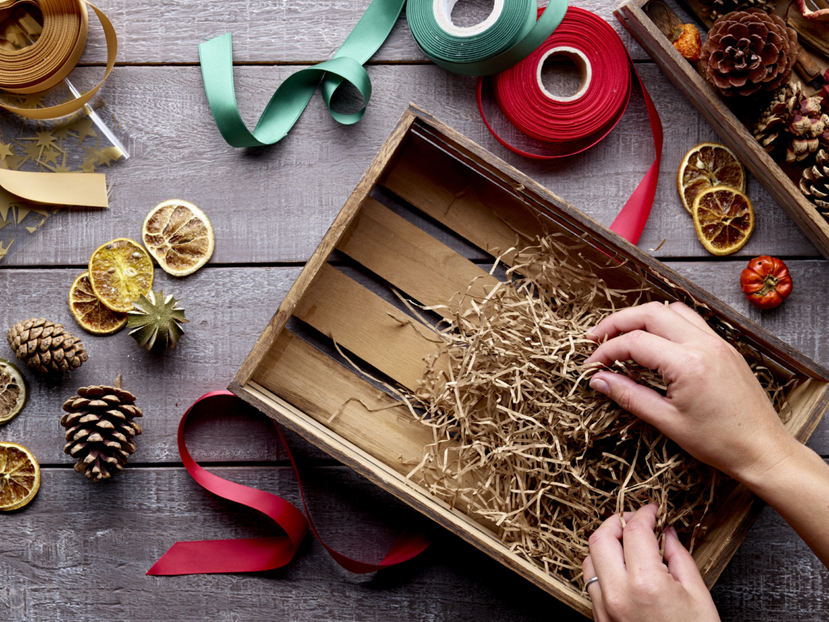 Wooden hamper crate being filled with wood wool to create a Christmas hamper